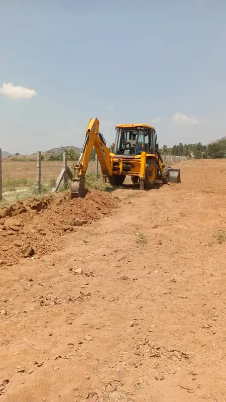 A digger cuts the trench for the drip line